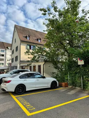 a white car parked in a parking lot next to a house at tas24ch Travel and Sleep 24 in St. Gallen