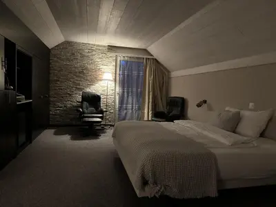 a bedroom with a bed and two chairs and a window at Hotel Säntis Teufen in Teufen