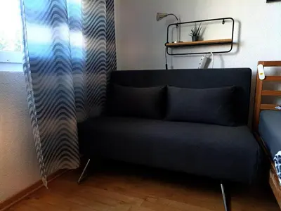a couch sitting in a room with a curtain at Sonniges Studio mit Aussicht in Oberegg