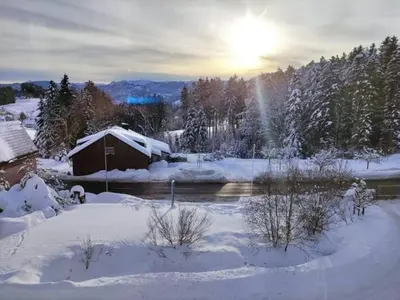 a snow covered yard with a barn and a river at Sonniges Studio mit Aussicht in Oberegg