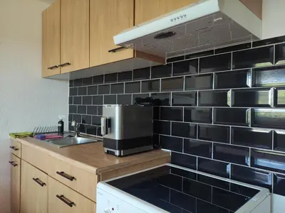a kitchen with black tile on the wall and a sink at Sonniges Studio mit Aussicht in Oberegg