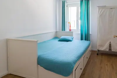 a bedroom with a bed with blue sheets and a window at Konstanz nähe, ruhiges 4-Zim-Wohnung bis 8 Personen in Kreuzlingen