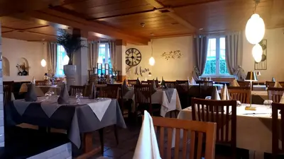 a restaurant with tables and chairs and a clock on the wall at il fiore Hotel Steinach SG in Steinach