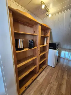 a small kitchen with wooden shelves and a refrigerator at Villa Donkey Ferienwohnung in Degersheim