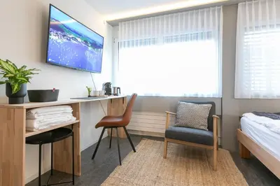 a bedroom with a desk and a bed and a tv at INN JOY Apartments - Sankt Gallen Center in St. Gallen