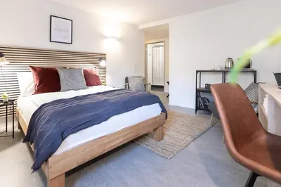 a bedroom with a bed and a desk and a table at INN JOY Apartments - Sankt Gallen Center in St. Gallen