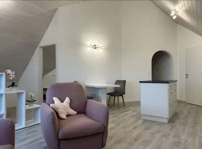 a living room with a chair and a table at Dachwhg an schöner Aussichtslage in Berneck