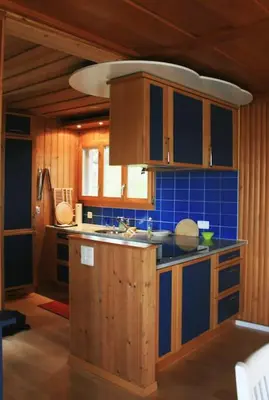 a kitchen with wooden cabinets and a blue tile wall at Haus am Seeufer mit Veranda in natürlicher Umgebung in Güttingen