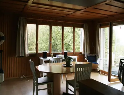 a dining room with a table and chairs and windows at Haus am Seeufer mit Veranda in natürlicher Umgebung in Güttingen