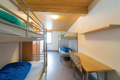 a dorm room with bunk beds and a table at Berggasthaus Oberdorf in Wildhaus