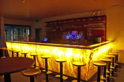 a bar with stools in a room with lights at Berggasthaus Oberdorf in Wildhaus