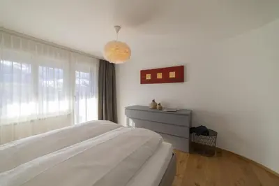 a white bedroom with a bed and a window at Gamsalpblick in Wildhaus