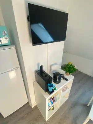 a flat screen tv hanging on a wall next to a refrigerator at Ruhige, neue Dachwohnung an Altstadt, nähe Messe in St. Gallen