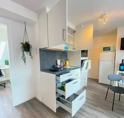 a kitchen with white cabinets and a dining room at Ruhige, neue Dachwohnung an Altstadt, nähe Messe in St. Gallen