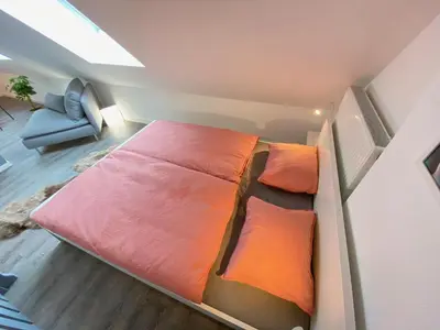 a small bedroom with a bed and a chair at Ruhige, neue Dachwohnung an Altstadt, nähe Messe in St. Gallen