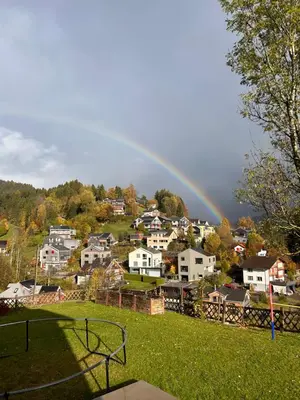 a rainbow in the sky over a town with houses at Ferienwohnung mit Aussicht in Gais
