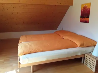 a bed with an orange comforter in a room at Zwinglis Ferienwohnung Rosi in Nesslau
