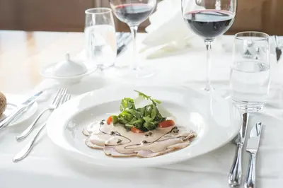 a plate of food on a table with wine glasses at Anker Hotel Restaurant in Teufen