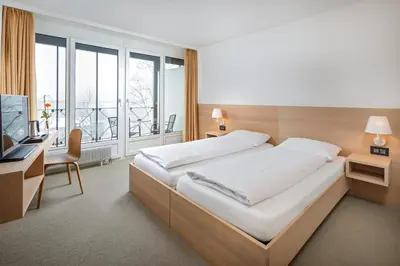 a bedroom with a large bed with a desk and a television at Newstar Hotel (Free Parking) in St. Gallen