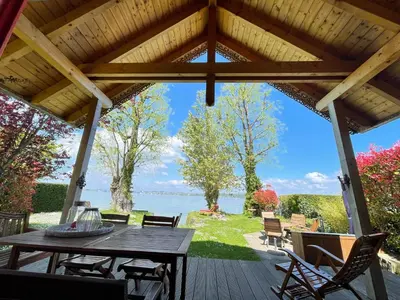 a wooden deck with a table and chairs and a view of the water at Ferienhäuschen mit privatem Seezugang in Bottighofen