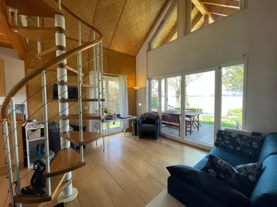 a living room with a blue couch and a spiral staircase at Ferienhäuschen mit privatem Seezugang in Bottighofen