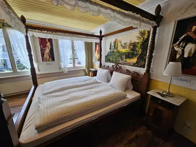 a bedroom with a canopy bed in a room with windows at Hotel Taverne zur Linde in Bischofszell
