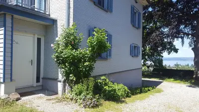 a house with a tree next to a door at Seesicht und charmante Wohnung bei Hanni und Ueli in Bottighofen