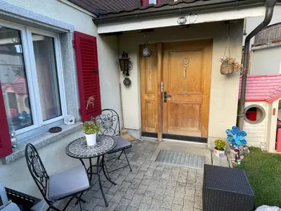 a patio with a table and chairs in front of a door at Ferienwohnung Edelweiss in Wolfhalden