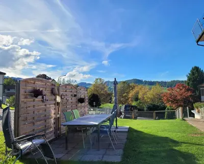 a patio with a table and chairs in a yard at Ferienwohnung Edelweiss in Wolfhalden