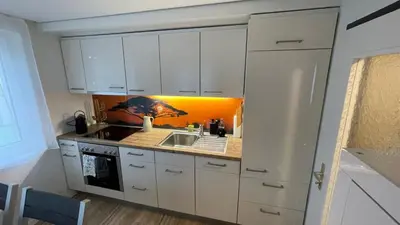 a kitchen with white cabinets and a sink at Ferienwohnung Edelweiss in Wolfhalden