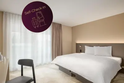 a hotel room with a large bed and a purple sign at b_smart motel Amriswil in Amriswil