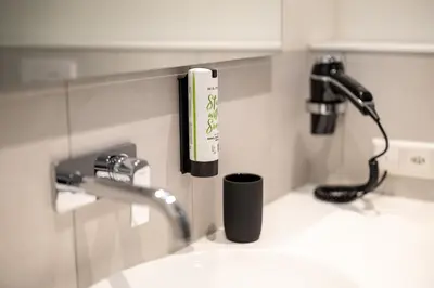a bathroom sink with a phone on the wall at b_smart motel Amriswil in Amriswil