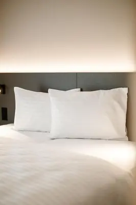 a large white bed with white pillows on it at b_smart motel Amriswil in Amriswil