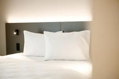 a white bed with white pillows on top of it at b_smart motel Amriswil in Amriswil