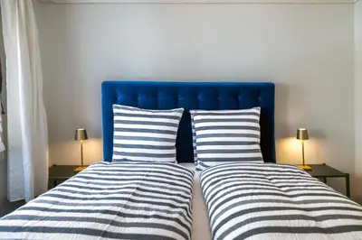 a bed with a blue headboard and two striped pillows at Blattenheimat6 - im traditionellen Appenzeller Haus in Appenzell