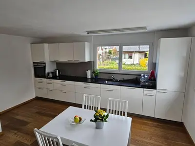 a kitchen with white cabinets and a white table and chairs at Private Etage 5 Min vom Bahnhof - Parken - Küche - Netflix in Widnau