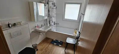 a small bathroom with a sink and a chair at Private Etage 5 Min vom Bahnhof - Parken - Küche - Netflix in Widnau
