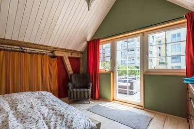 a bedroom with a bed and a chair and a window at Farbige Wohnung Zentral in Herisau