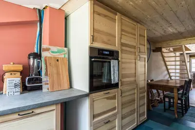 a kitchen with wooden cabinets and a table in a tiny house at Farbige Wohnung Zentral in Herisau