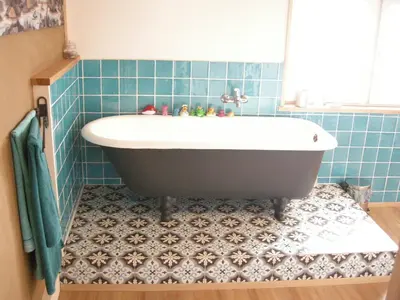 a bath tub in a blue tiled bathroom at Farbige Wohnung Zentral in Herisau
