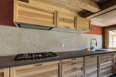 a kitchen with wooden cabinets and a stove top oven at Farbige Wohnung Zentral in Herisau