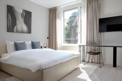 a white bedroom with a large bed and a window at VISIONAPARTMENTS St Gallen - contactless check-in in St. Gallen