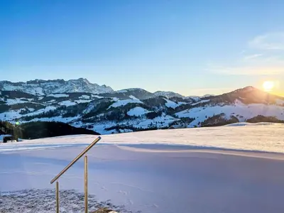 a view of a snow covered field with the sun rising over mountains at Apartment Panoramablick by Interhome in Haslen