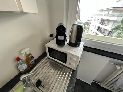 a small kitchen with white cabinets and a window at Ferienwohnung am Bodensee in Rorschach