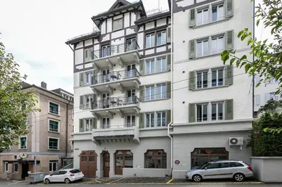 a white building with cars parked in front of it at INN JOY Apartments - Roter Platz in St. Gallen