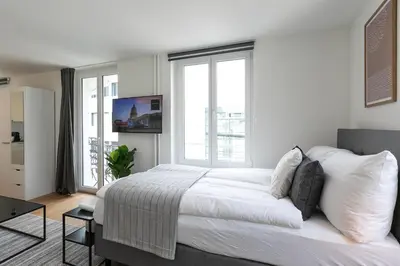 a white bedroom with a large bed and windows at INN JOY Apartments - Roter Platz in St. Gallen