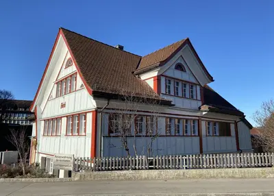 a large white and red house with a fence at Ferienwohnung Bärli Appenzell in Appenzell