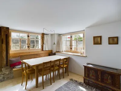 a dining room with a table and some windows at Ferienwohnung Bärli Appenzell in Appenzell