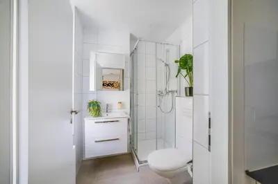 a white bathroom with a toilet and a shower at HRE Apartments St Gallen City Center in St. Gallen