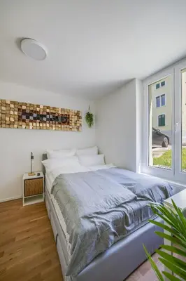 a white bedroom with a large bed and a window at HRE Apartments St Gallen City Center in St. Gallen